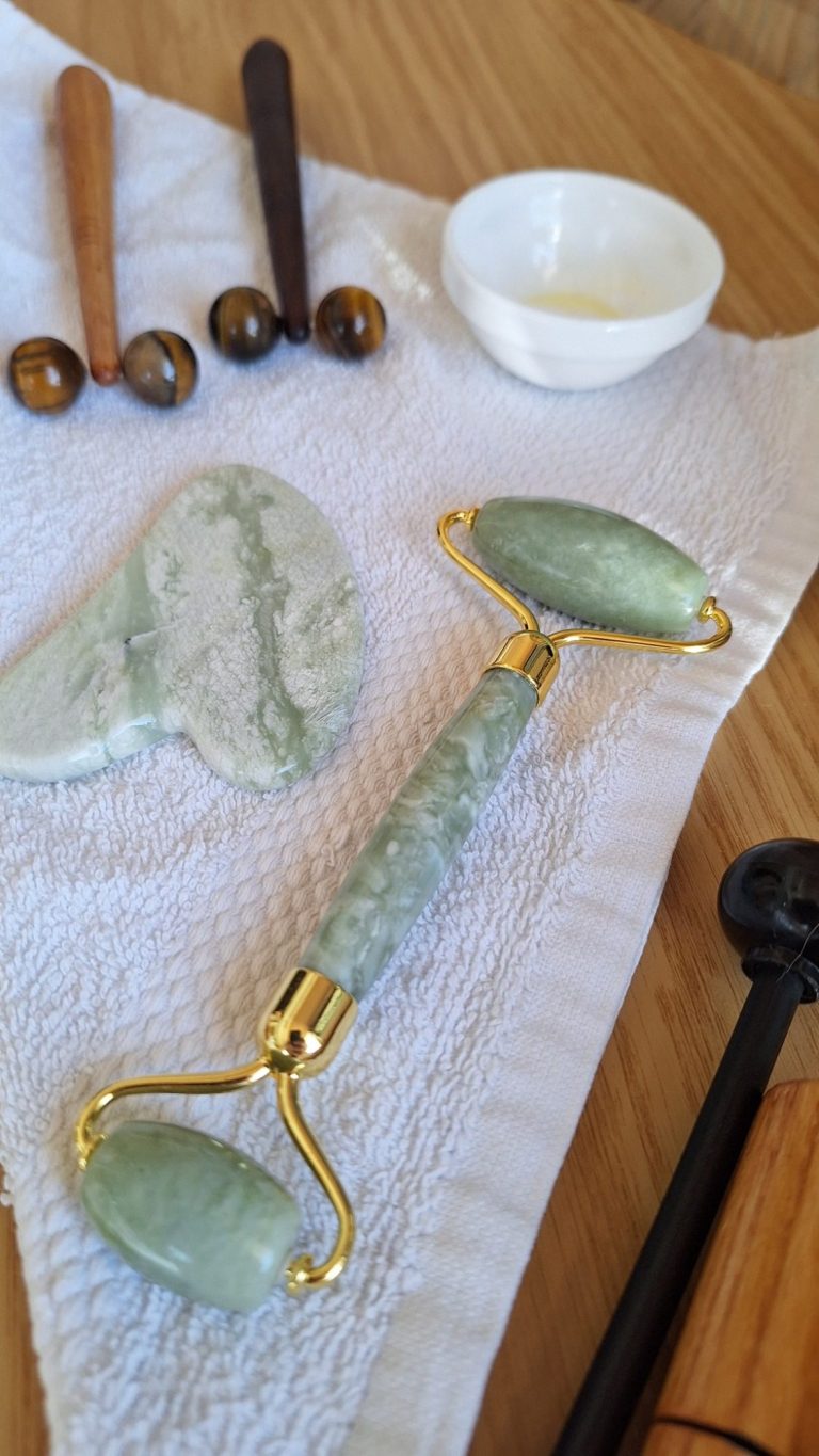 Outils de soin du visage incluant un rouleau en jade et une pierre de massage.